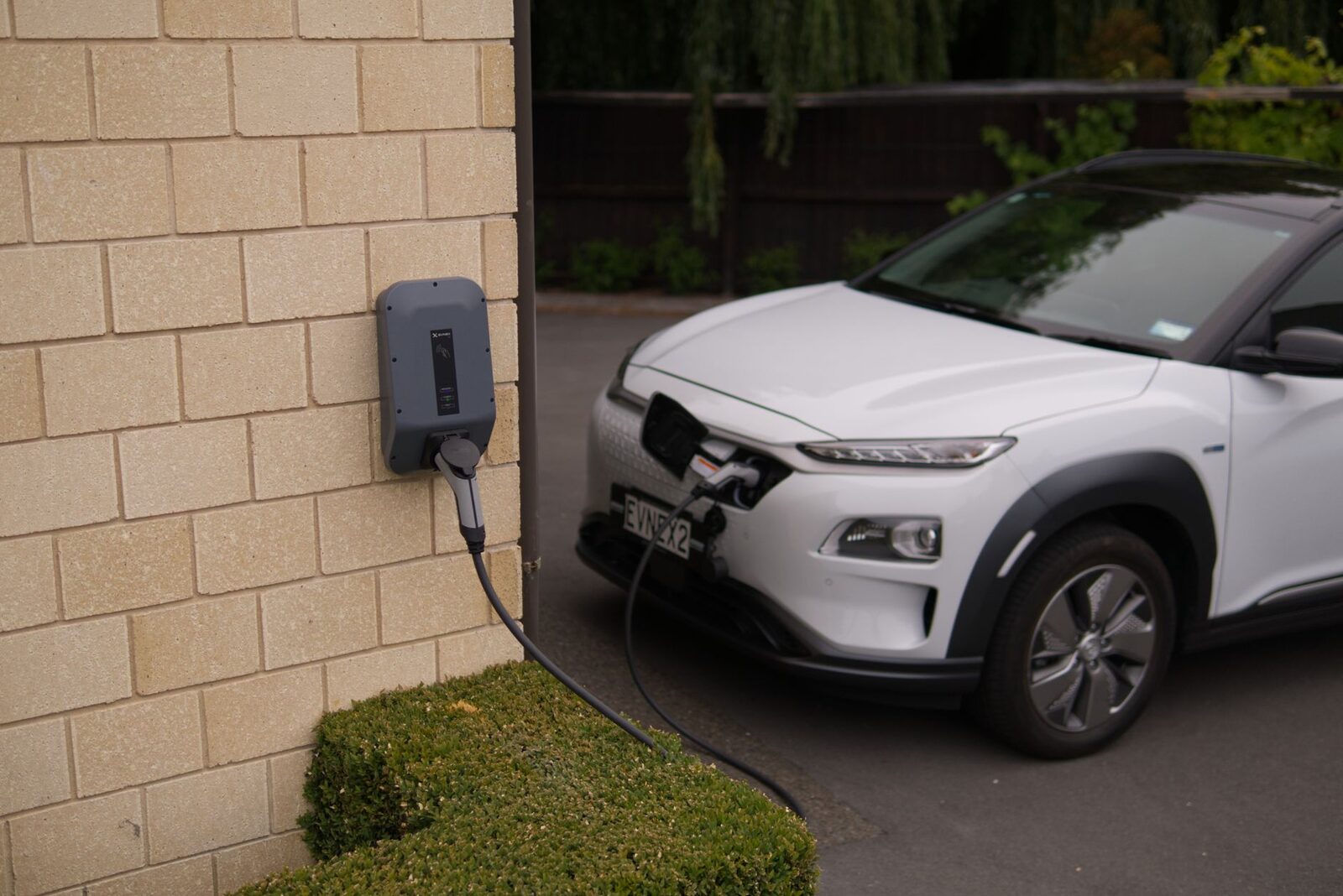 Carregador de parede conectado a carro elétrico na entrada de uma casa de temporada