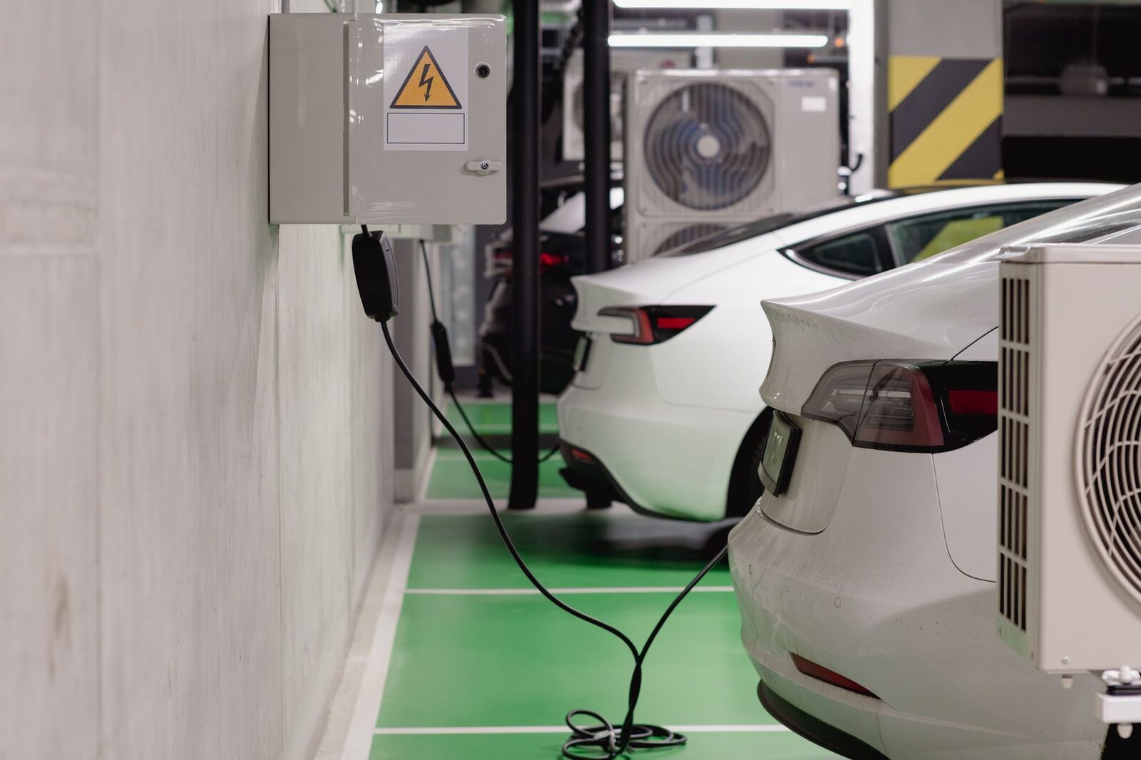 Carros elétricos carregando em vagas sinalizadas de garagem de condomínio