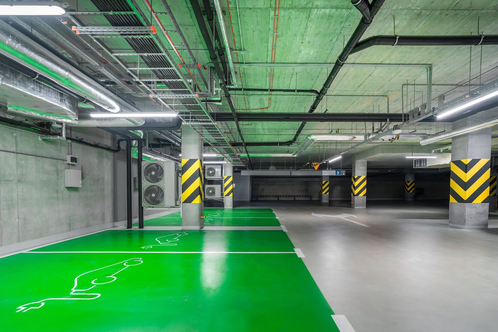 Garagem subterrânea de condomínio com vagas demarcadas para recarga de veículos elétricos